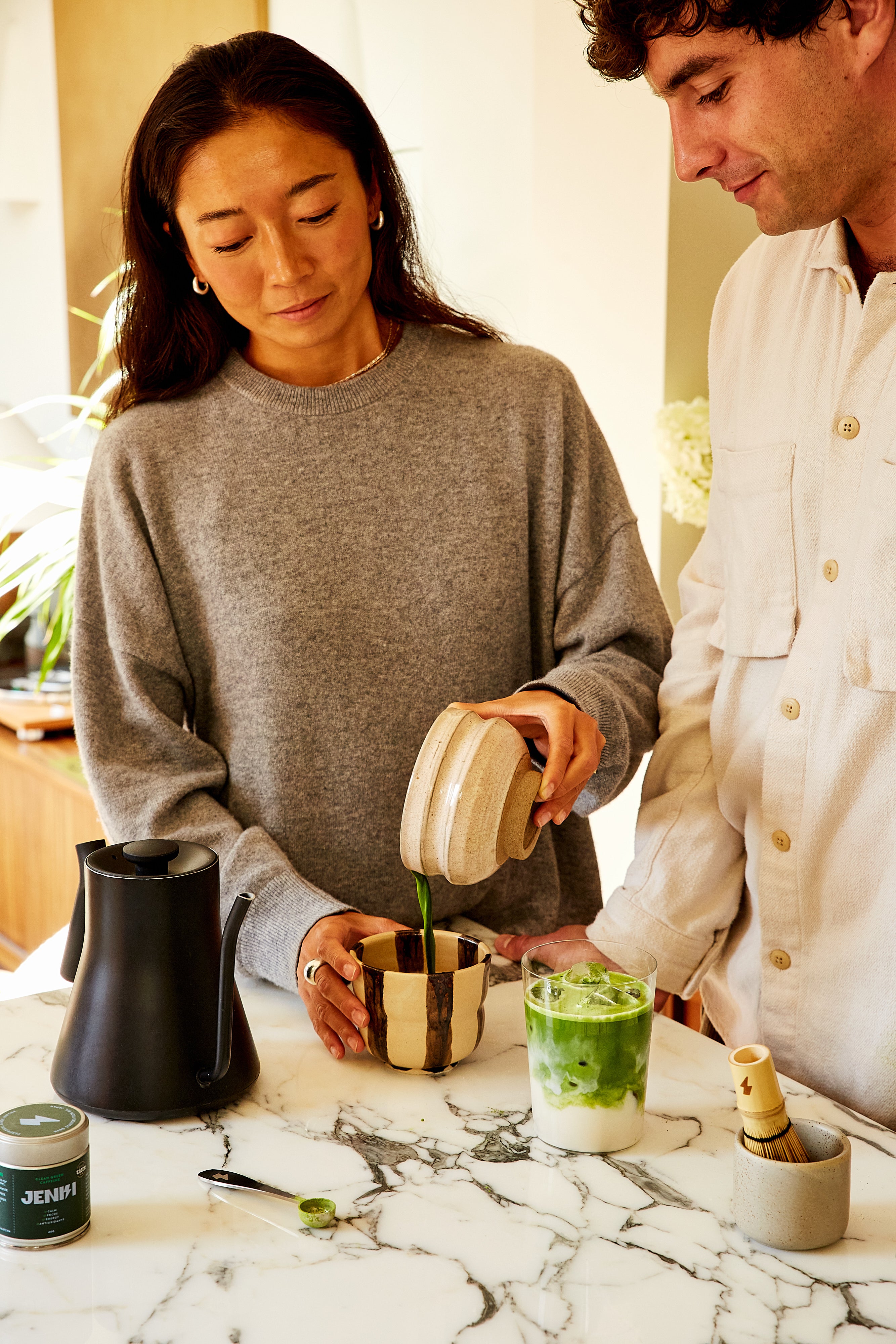Two people preparing a drink at a marble counter with a blurred indoor background
