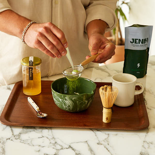 Person preparing a drink with tea and honey on a marble countertop