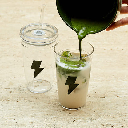 Green liquid being poured into a glass with a lightning bolt symbol on a wooden surface